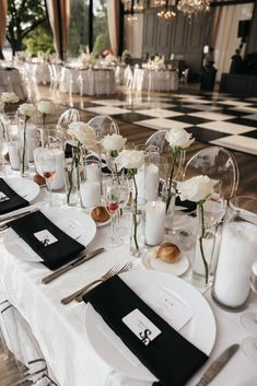 the table is set with white flowers and black napkins