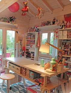 a room filled with lots of toys and decor on top of a wooden table next to two windows