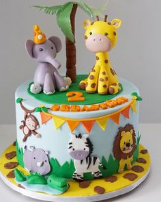 a birthday cake decorated with animals and a palm tree