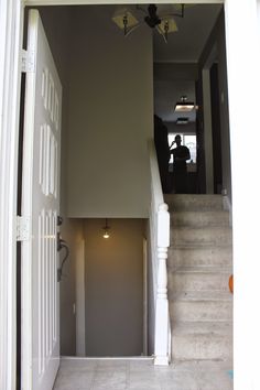 an open door leading to a hallway with white walls and stairs that lead up to the second floor