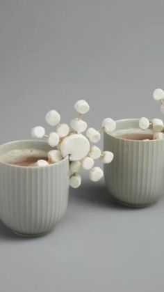 two mugs filled with hot chocolate and marshmallows on a gray background