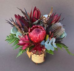 a vase filled with red flowers and greenery