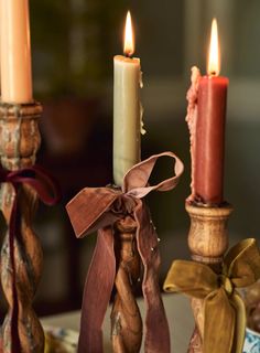 three candles with ribbons on them sitting next to each other