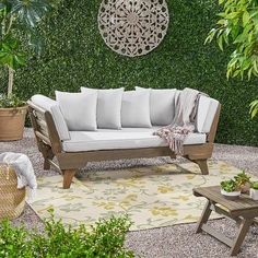 a white couch sitting on top of a rug next to a wooden table and potted plants