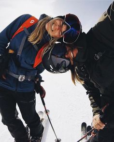 two skiers kissing each other in the snow