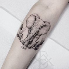 an elephant tattoo on the arm with leaves and flowers in it's trunk,