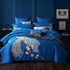 a bed with blue comforters and pillows on top of it in front of a wall