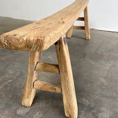 a wooden bench sitting on top of a cement floor next to a white wall,