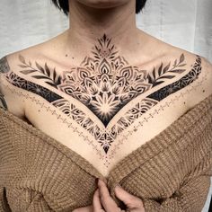 a woman's chest with an intricate tattoo design on the upper part of her body