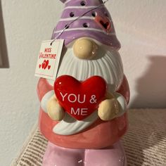 a ceramic figurine holding a heart with the words you and me written on it