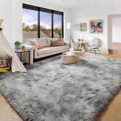 a living room filled with furniture and a rug on top of a hard wood floor