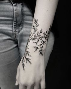 a woman's hand with a black and white flower tattoo on her left wrist