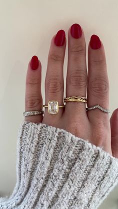 a woman's hand with three different rings on her fingers and one is wearing a sweater