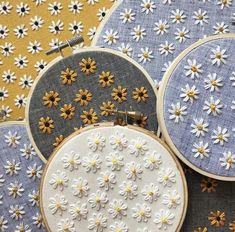 three embroidery hoops with daisies on them sitting next to each other in front of a yellow background