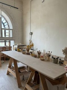 an art studio with various items on the table and in front of a large window