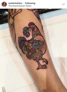 a tattoo on the leg of a person with a rooster and flowers in its beak