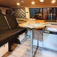 the interior of an rv with wood flooring and black leather seat covers on it