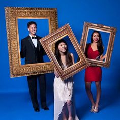 three people posing for a photo with two framed pictures