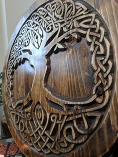 a wooden plaque with an image of a woman's face in the center, surrounded by intricate carvings