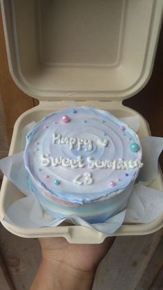 a birthday cake with white frosting and sprinkles in a foam container