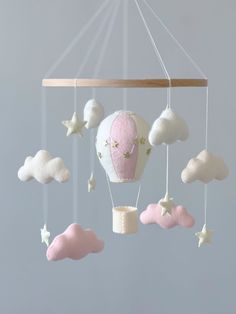 a pink and white hot air balloon mobile with stars hanging from it's sides