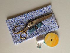 a pair of scissors sitting on top of a blue and white cloth next to some sewing supplies