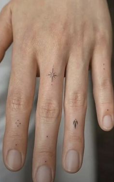 a person's hand with a small star tattoo on their left thumb and fingers