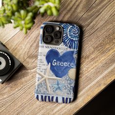 a phone case sitting on top of a wooden table next to a camera and plant