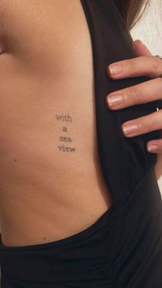 a woman with a tattoo on her stomach that reads, with a sea view written in cursive font