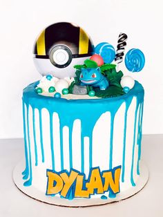 a birthday cake with blue icing and an image of a pokemon ball on top