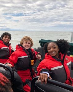 three people in life jackets are on a boat near the water and smiling at the camera