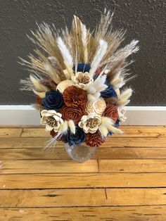 a vase filled with flowers and feathers on top of a wooden floor