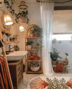 a bathroom with plants and towels on the shelf next to the sink in front of the window