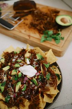 nachos on a plate with avocado, sour cream and chocolate sauce