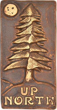 a metal plaque with a tree and the words up north