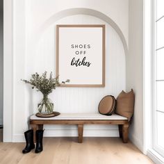 a wooden bench sitting in front of a white wall next to a vase with flowers