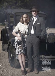 a man and woman standing next to an old car