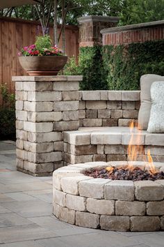 an outdoor fire pit surrounded by stone steps and flowers in a potted planter