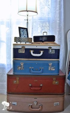 four suitcases stacked on top of each other in front of a lamp and window