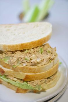 a sandwich on a plate with lettuce and meat in the middle, sitting on a table