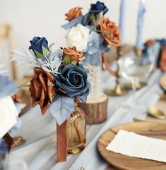 the table is set with blue and white flowers in vases, napkins, and candles