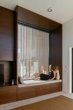 a woman sitting on top of a window sill next to a wall mounted tv