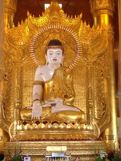 the golden buddha statue is surrounded by flowers