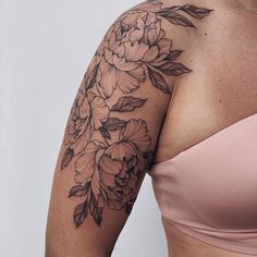 a woman's arm with flowers and leaves tattooed on her left arm, in front of a white background