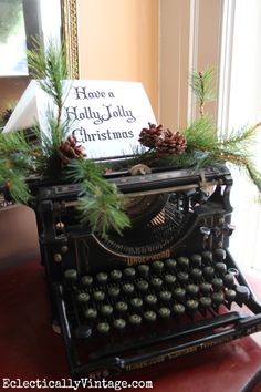 an old fashioned typewriter decorated with pine cones and greenery