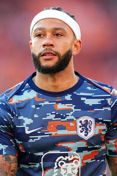 a man with a beard wearing a blue shirt and headband looking off to the side