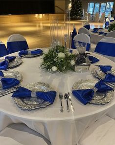 the table is set with silverware and blue napkins for an elegant wedding reception