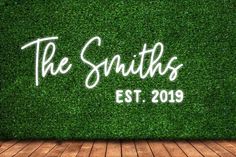 the smiths logo is shown on top of a green artificial wall with wood flooring