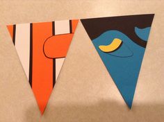 two triangle shaped kites are hanging on the wall next to each other, one with an orange and blue face