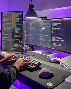 a person sitting at a desk with a keyboard and mouse in front of two monitors